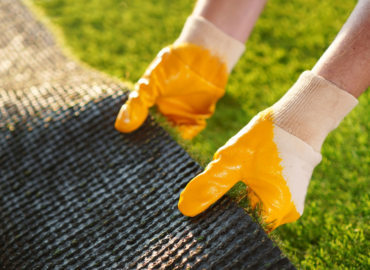 Hands With Yellow Gloves Installing Artificial Green Grass